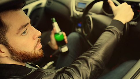 Man driving over the limit, holding a beer