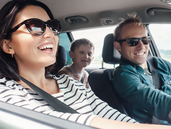 A young family smiles in their car