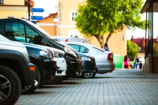 A line of cars parked up in a cobbled car park