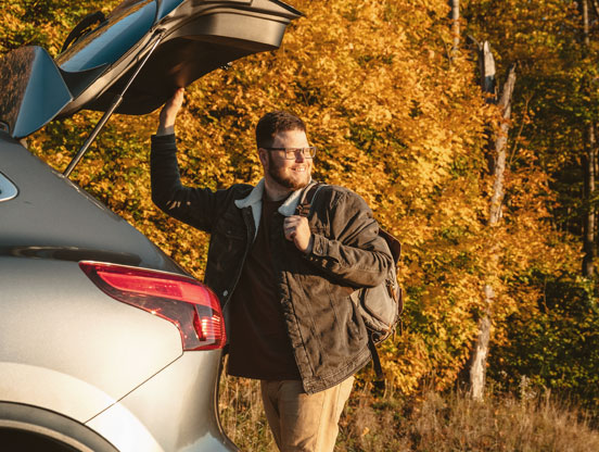 Man opening his car boot by the side of the road, smiling as he looks towards a patrol arriving on the scene