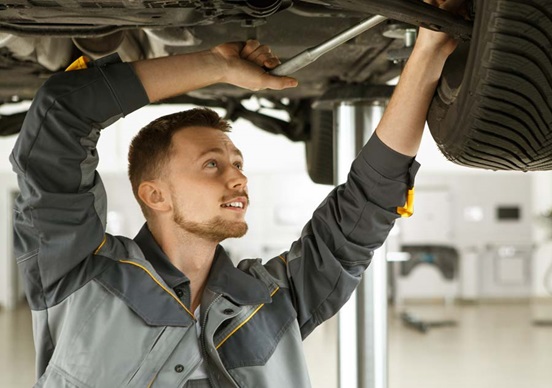 Mechanic in garage fixing vehicle chassis