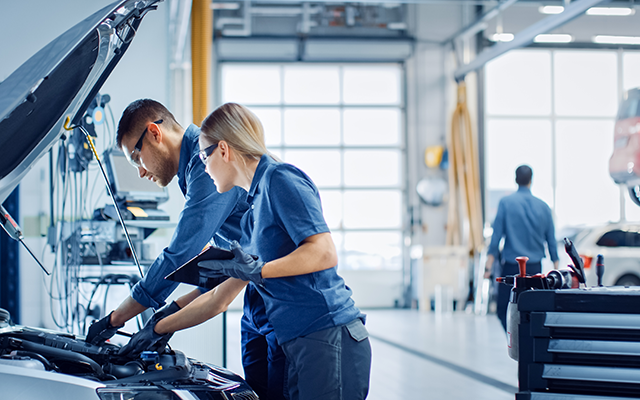 Two mechanics working under the bonnet of a car